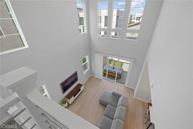 living room with a towering ceiling, wood finished floors, and baseboards