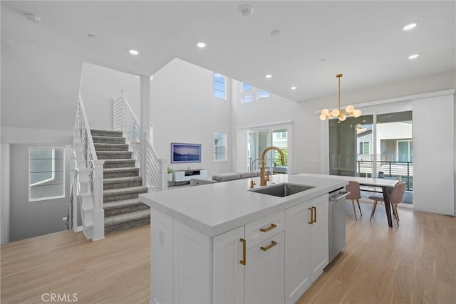 kitchen featuring a sink, light wood finished floors, a chandelier, white cabinets, and recessed lighting