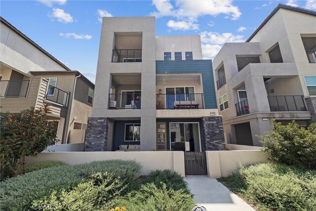 contemporary house featuring a fenced front yard, a gate, and stucco siding