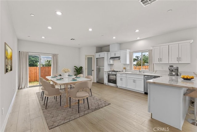 230 E Hoffer St, Banning, CA 92220 - kitchen featuring appliances with stainless steel finishes, under cabinet range hood, healthy amount of natural light, white cabinets, and recessed lighting