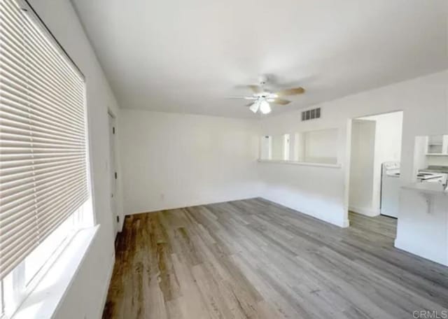 unfurnished room featuring a ceiling fan, washer / clothes dryer, and light wood-style floors