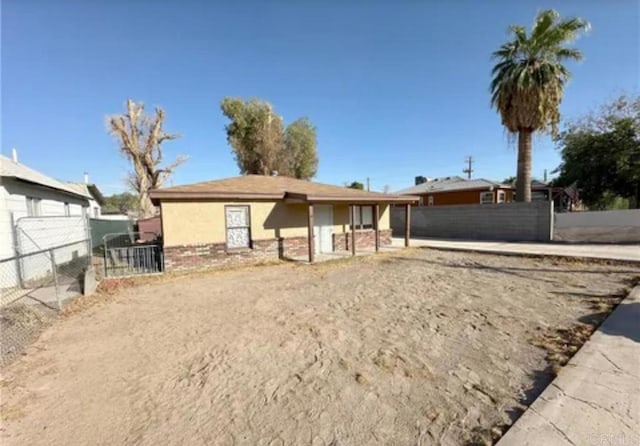 view of front of house featuring fence, stucco siding, and brick siding