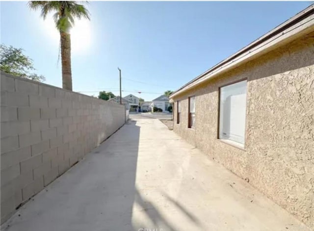 view of side of property featuring fence and stucco siding
