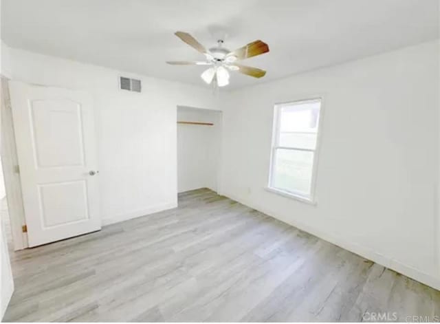 unfurnished bedroom featuring wood finished floors, a closet, and a ceiling fan