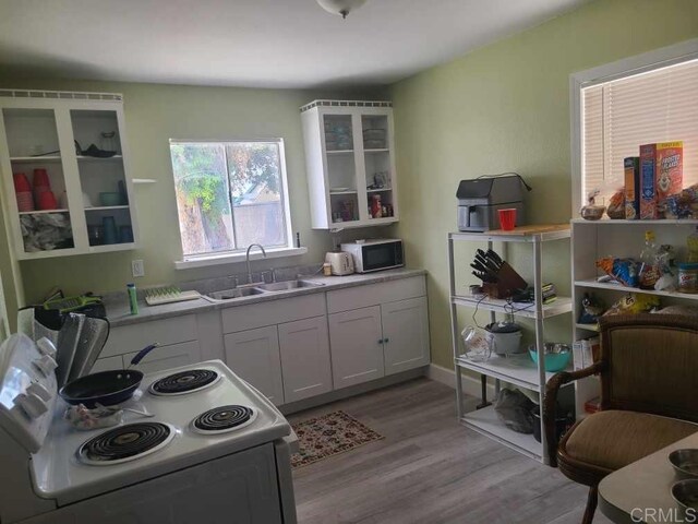 kitchen with electric range, a sink, light wood-style flooring, and light countertops