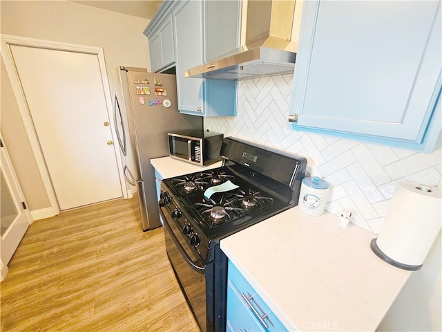 kitchen with wall chimney range hood, stainless steel appliances, decorative backsplash, light wood-style floors, and light countertops