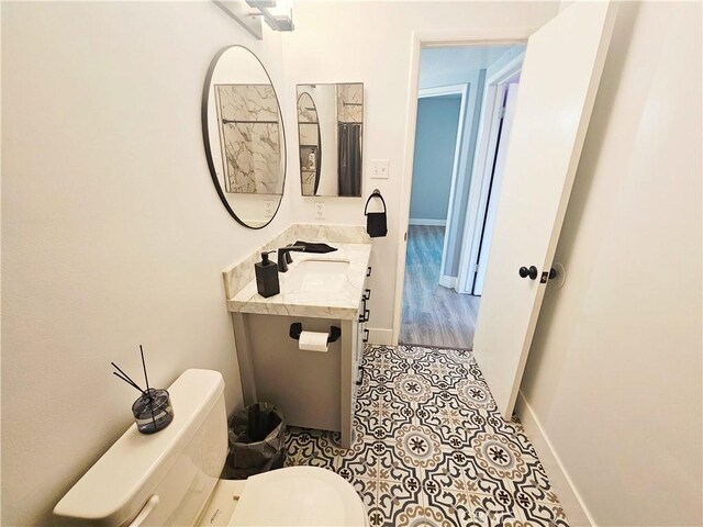 bathroom featuring toilet, tile patterned flooring, vanity, and baseboards