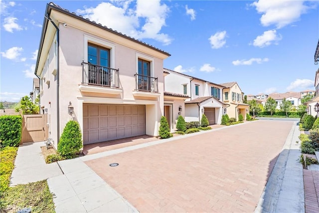 view of front of property with a balcony, a residential view, stucco siding, and an attached garage