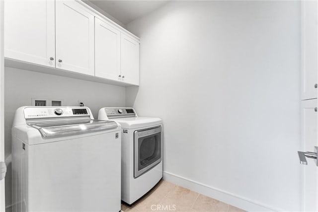 washroom featuring independent washer and dryer, cabinet space, baseboards, and light tile patterned flooring