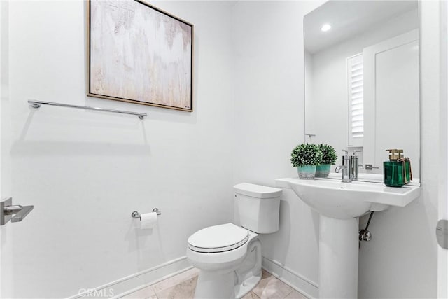 half bathroom with toilet, baseboards, and tile patterned flooring