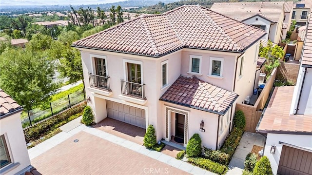 view of front of house featuring a balcony, a tiled roof, stucco siding, and an attached garage