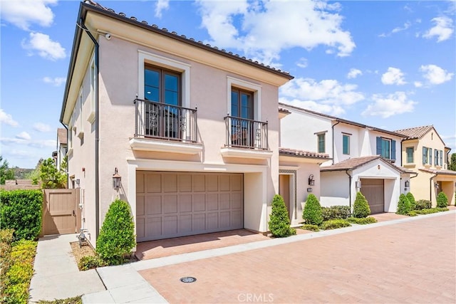 view of front facade featuring a balcony, stucco siding, and an attached garage