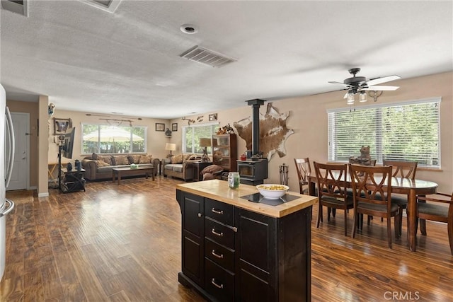 6176 Some Way, Magalia, CA 95954 - kitchen with a wood stove, dark cabinetry, dark wood-style flooring, wooden counters, and ceiling fan