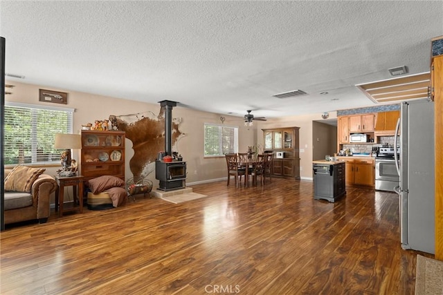 6176 Some Way, Magalia, CA 95954 - living room featuring a wood stove, a textured ceiling, dark wood-type flooring, a ceiling fan, and baseboards