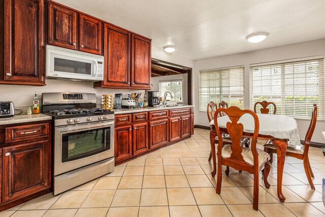 252 Worthington St, Spring Valley, CA 91977 - kitchen with white microwave, stainless steel range with gas cooktop, a sink, dark brown cabinets, and light tile patterned flooring