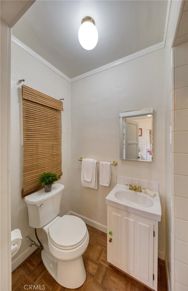 bathroom with toilet, baseboards, ornamental molding, and vanity