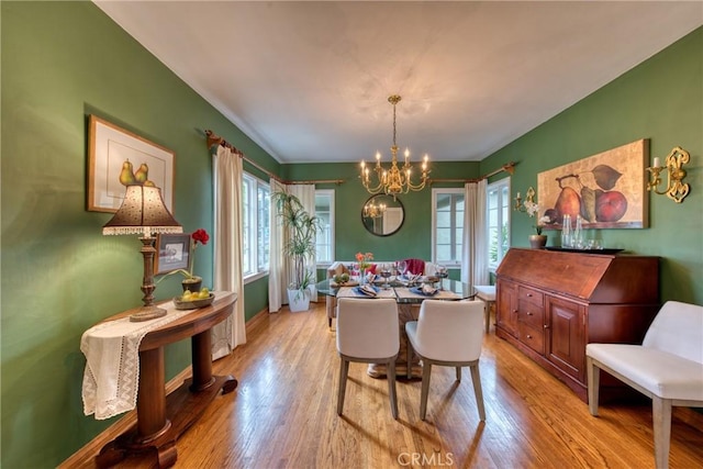 dining space featuring a chandelier, light wood-type flooring, and baseboards