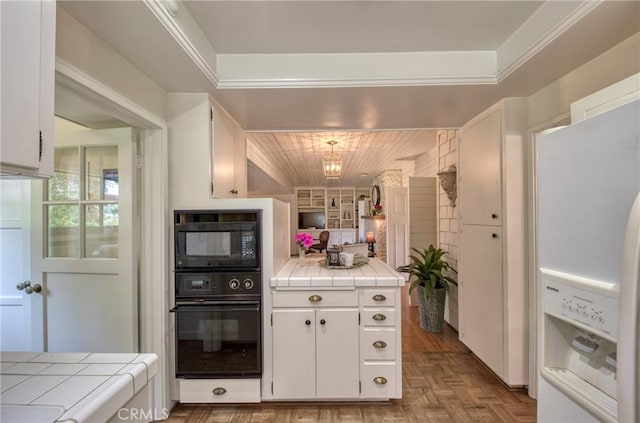 kitchen featuring tile countertops, black appliances, and white cabinetry
