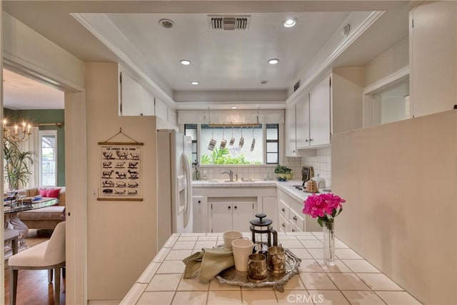 kitchen featuring tile counters, white appliances, tasteful backsplash, white cabinets, and a sink