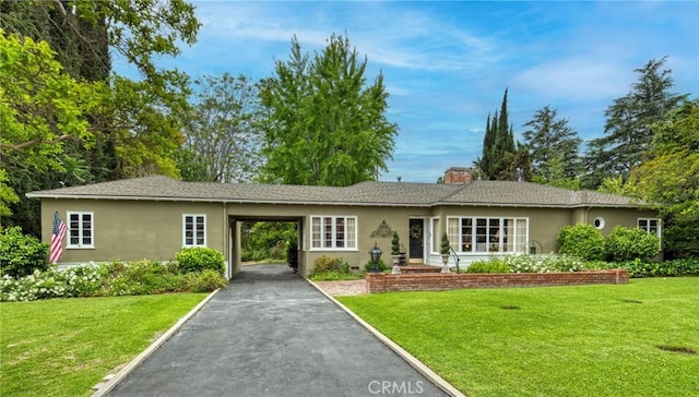 ranch-style home featuring stucco siding, a front lawn, and driveway