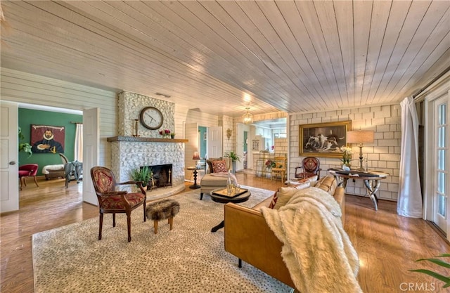 living room featuring a fireplace, wood ceiling, plenty of natural light, and wood finished floors