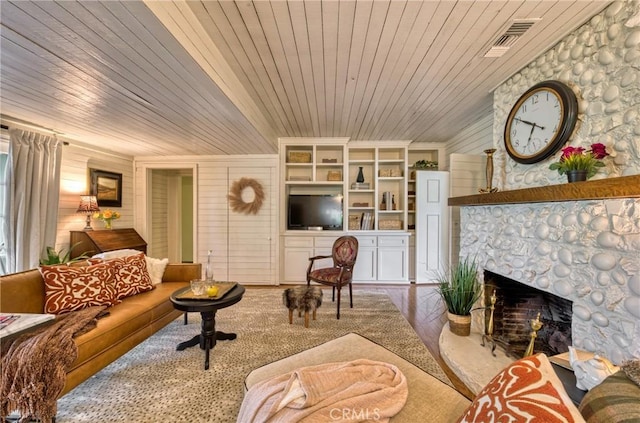 living room with wood ceiling, a fireplace, built in features, wood walls, and wood finished floors