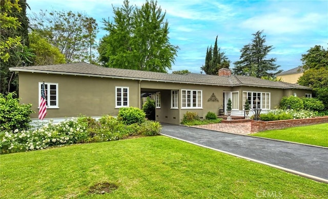 single story home with stucco siding, driveway, a front yard, an attached carport, and a chimney