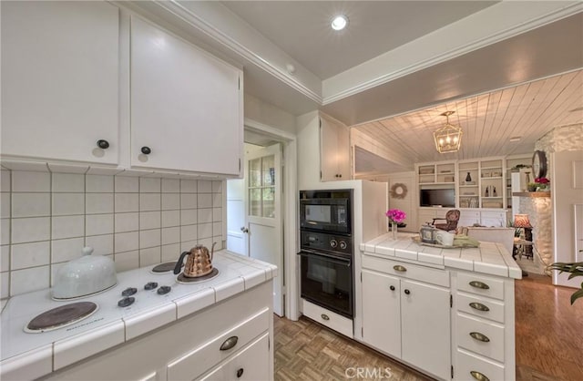 kitchen with black appliances, tile counters, white cabinetry, decorative backsplash, and wooden ceiling