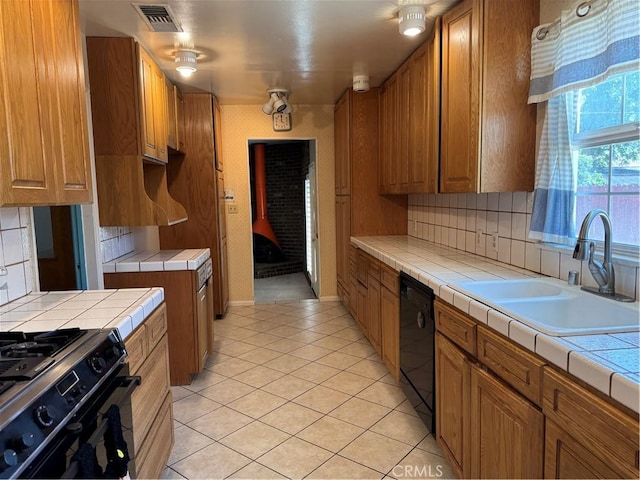 kitchen featuring black appliances, tile counters, a sink, brown cabinets, and tasteful backsplash