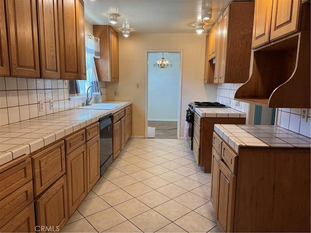 kitchen featuring gas range, tile countertops, a sink, dishwasher, and tasteful backsplash
