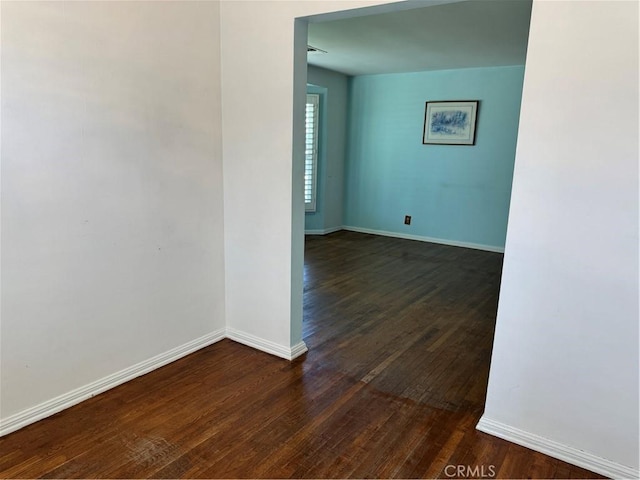 unfurnished room with dark wood-style flooring and baseboards