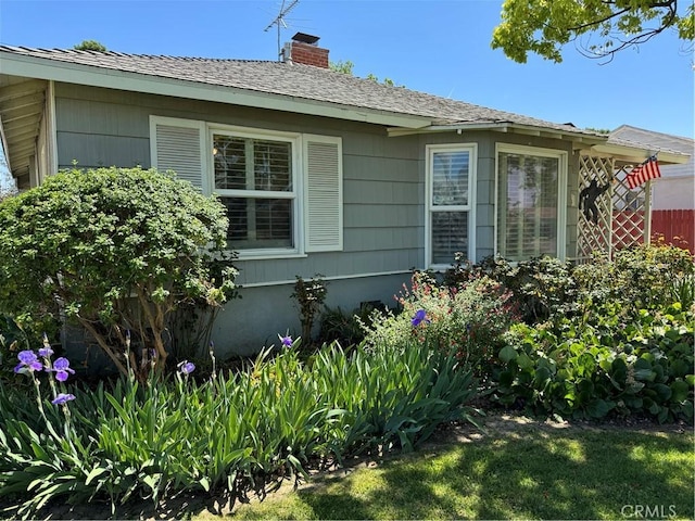 view of property exterior with a chimney and fence