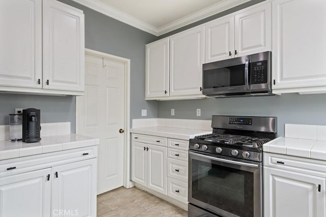9229 Maywood Way, Riverside, CA 92503 - kitchen featuring appliances with stainless steel finishes, tile counters, white cabinetry, and ornamental molding