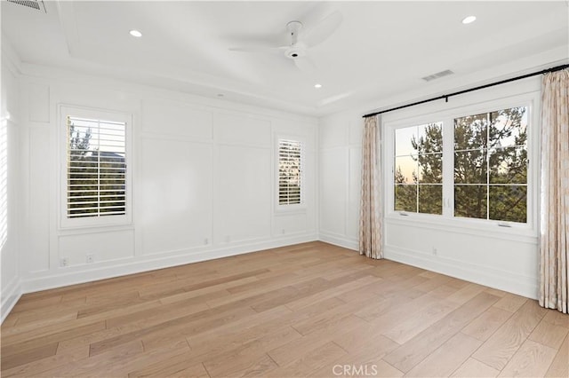 empty room featuring a decorative wall, light wood finished floors, plenty of natural light, ceiling fan, and recessed lighting
