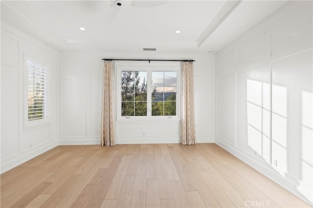empty room featuring a decorative wall, light wood-type flooring, and a ceiling fan