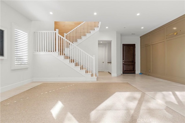 unfurnished living room featuring recessed lighting, stairs, and baseboards