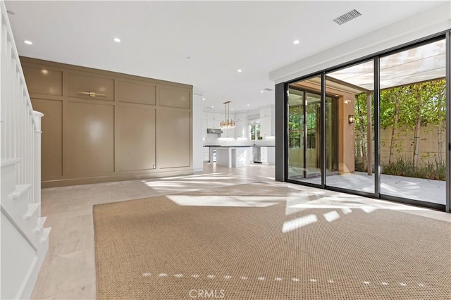 unfurnished living room featuring a chandelier, recessed lighting, and stairs
