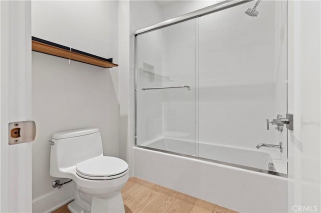 bathroom with wood finished floors, toilet, and combined bath / shower with glass door