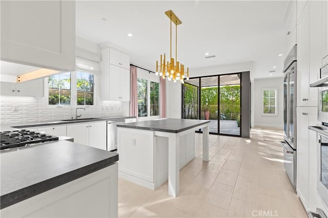 kitchen with dark countertops, appliances with stainless steel finishes, a sink, tasteful backsplash, and plenty of natural light