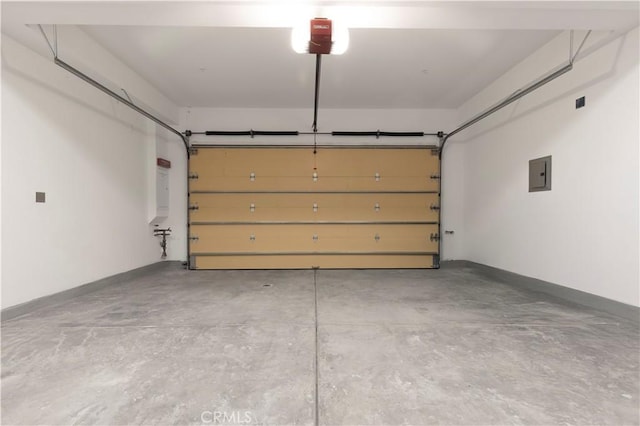 garage featuring electric panel, a garage door opener, and baseboards
