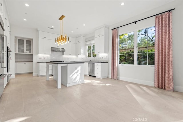 kitchen with stainless steel dishwasher, tasteful backsplash, under cabinet range hood, recessed lighting, and a center island