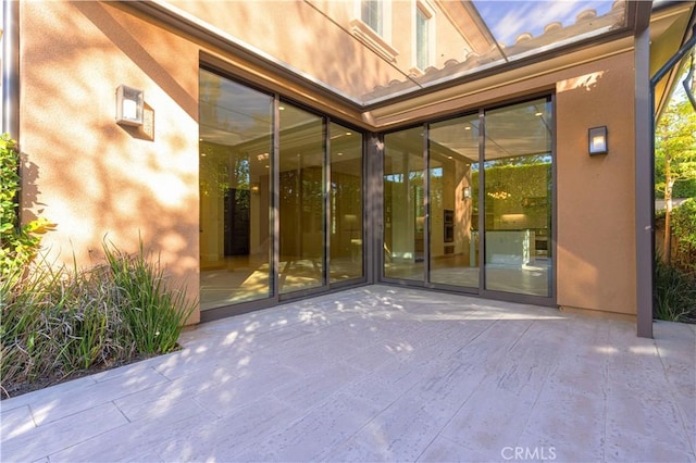 property entrance featuring a patio and stucco siding