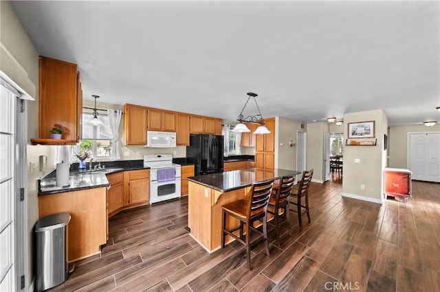 27876 Twilight Ct, Murrieta, CA 92563 - kitchen featuring white appliances, dark countertops, dark wood-style floors, a kitchen island, and a sink