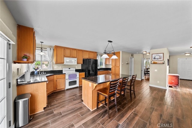 27876 Twilight Ct, Murrieta, CA 92563 - kitchen featuring white appliances, dark countertops, dark wood finished floors, a kitchen island, and hanging light fixtures