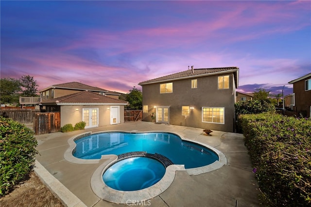 27876 Twilight Ct, Murrieta, CA 92563 - pool at dusk with french doors, a pool with connected hot tub, a fenced backyard, and a patio