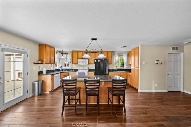 27876 Twilight Ct, Murrieta, CA 92563 - kitchen featuring white appliances, dark countertops, a center island, and dark wood finished floors