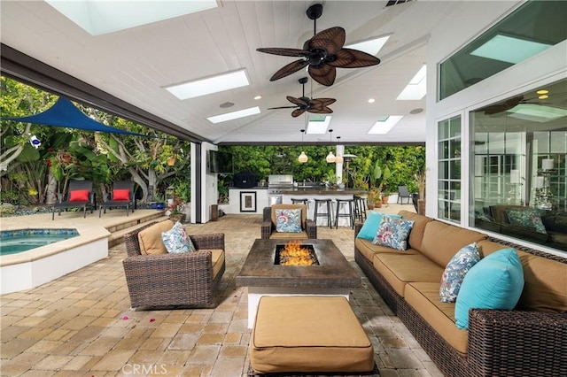 view of patio featuring an outdoor living space with a fire pit, exterior bar, an in-ground hot tub, ceiling fan, and a grill