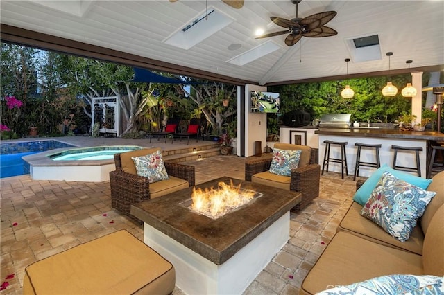 view of patio / terrace featuring an outdoor fire pit, a grill, a bar, exterior kitchen, and an in-ground hot tub