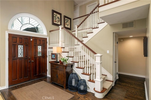 foyer featuring dark wood-style flooring, baseboards, stairs, and a high ceiling