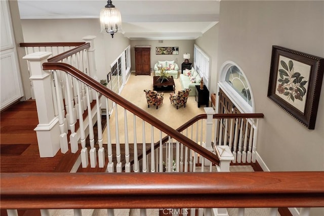 staircase with ornamental molding, a chandelier, and baseboards